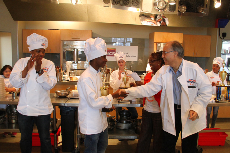 boy receiving trophy in front of class of young chefs